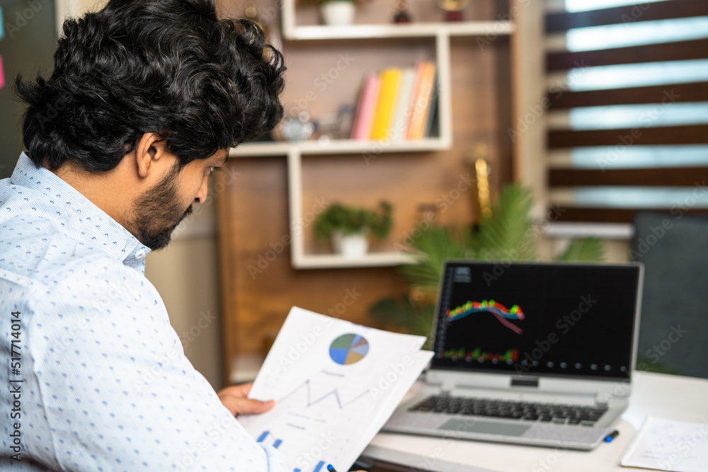 young man busy analysing Companies financial charts with technical stock mart charts on laptop - concept of investment, trading and money management young man busy analysing Companies financial charts with technical stock mart charts on laptop - concept of investment, trading and money management