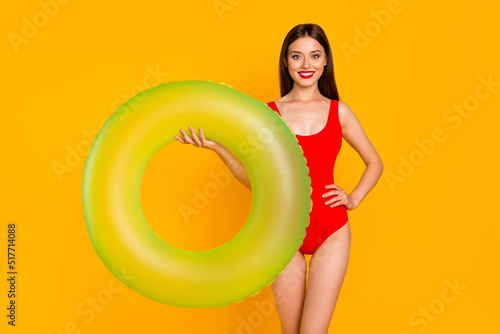 Photo of shiny positive woman wear swimsuit holding green buoy isolated yellow color background