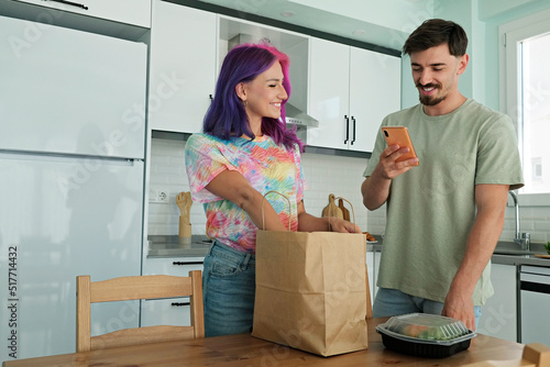 Fényképezés Hipster couple unpacking a paper bag full of take out food containers