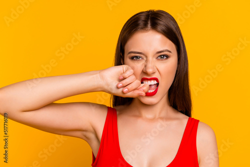 Portrait of young pretty person grinning teeth biting finger look camera isolated on yellow color background