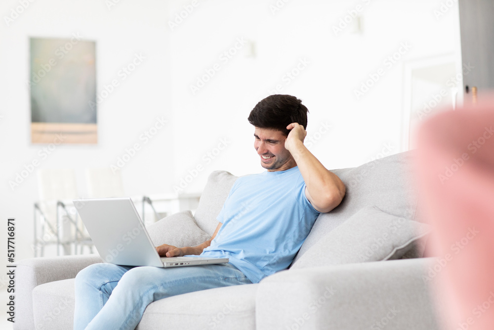 Young smiling man with laptop at home