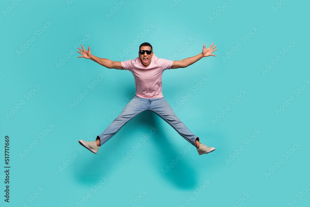 Full length photo of excited pretty man dressed pink t-shirt jumping high like star isolated turquoise color background