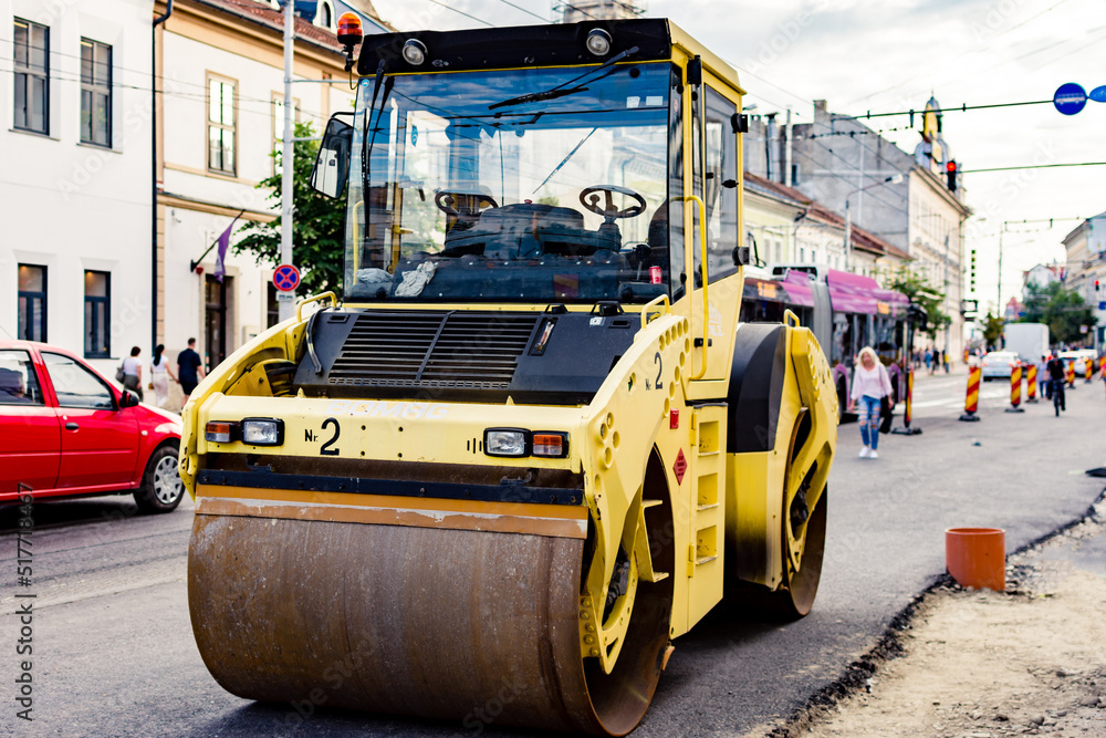 Yellow road roller used for straightening asphalt on street renewal or restorations