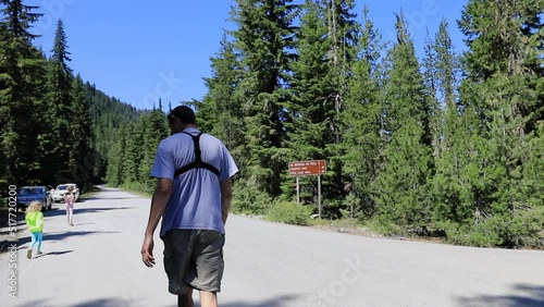 Coming out of the forest after family hiking trip with two girls in the Northwest American mountains.