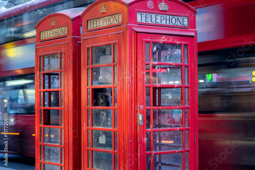 London red route master bus speeds past old British Red telephone boxes 