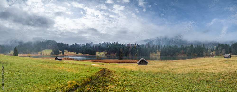 Fototapeta premium Alpine lake Geroldsee or Wagenbruchsee, Bavaria, Germany. Autumn overcast, foggy and drizzle day. Picturesque traveling, seasonal, weather, and rural nature beauty concept scene.