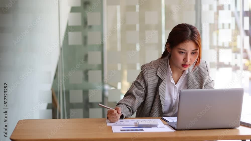 Business woman working in finance is calculating budget by calculator in bank office working while working on laptop and audit documents analyzing financial for accounting. Business woman working in finance is calculating budget by calculator in bank office working while working on laptop and audit documents analyzing financial for accounting.
