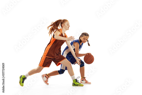 Studio shot of beginner basketball players, young girls, teen training with basketball ball isolated on white background. Concept of sport, team, enegry, competition, skills © master1305