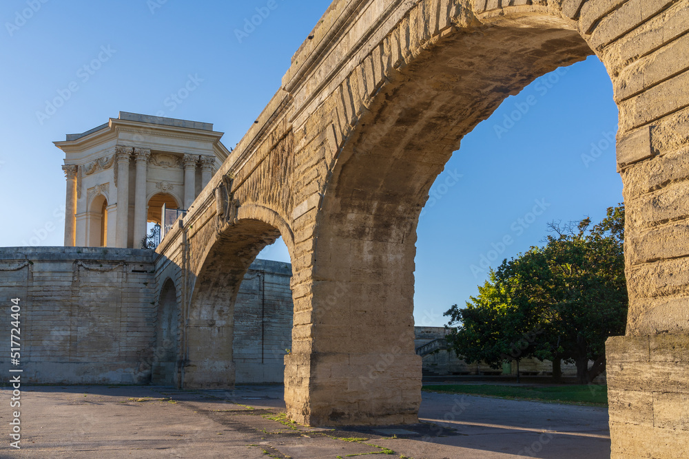 Scenic summer morning view of St Clement aka Arceaux aqueduct and classical water tower ancient stone buildings in historic Promenade du Peyrou garden, famous landmark of Montpellier, France