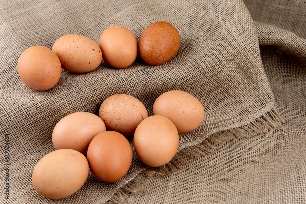 Fresh chicken brown eggs on burlap background, top view