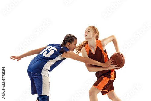 Two basketball players, young girls, teen playing basketball isolated on white background. Concept of sport, team, enegry, competition, skills
