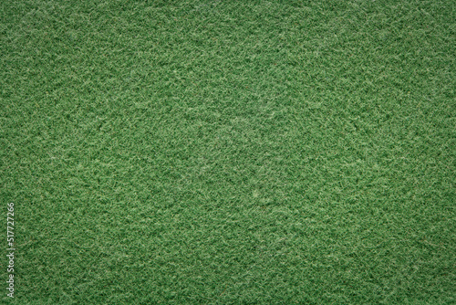 Green background of softness felted wool. Textured fluffy wool fabric. Warm fabric with short pile for outerwear. Closeup top view.