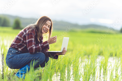 Asian woman farmer using laptop to store farm data In the evening with warm light. Agricultural technology concept. Organic agriculture.