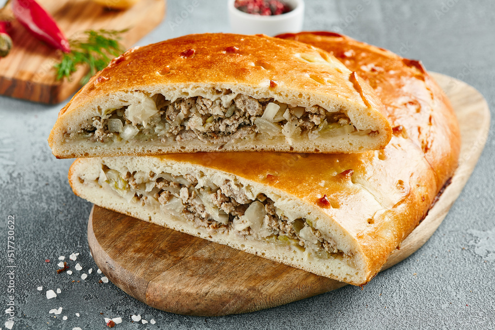 Classic pie with minced meat and potato on wooden board. Composition with meat pie on concrete background with textile and spices. Homemade pie with meat and potato in rustic style on gray table. Classic pie with minced meat and potato on wooden board. Composition with meat pie on concrete background with textile and spices. Homemade pie with meat and potato in rustic style on gray table.