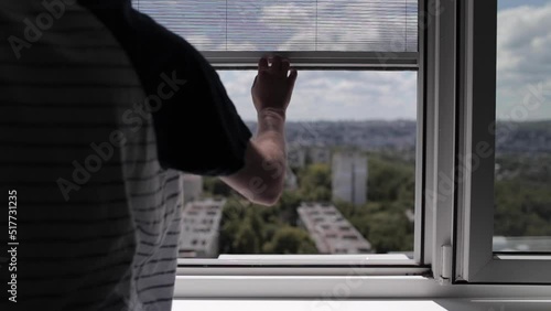 Close-up of male hand opens the modern mosquito net on plastic window.