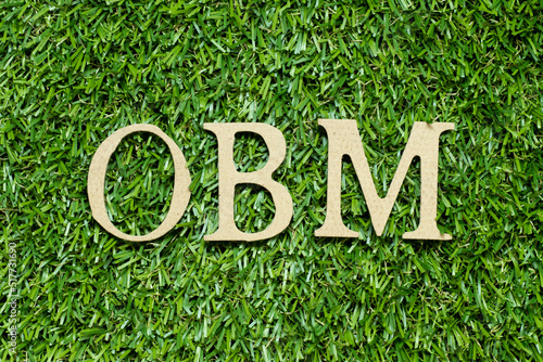 Wood alphabet letter in word OBM (Abbreviation of Original brand manufacturer) on green grass background photo