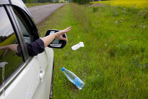 a person throws garbage from the car window to the side of the road