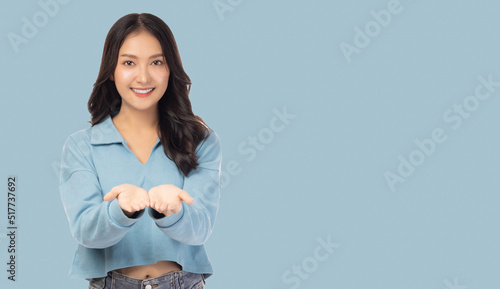 Young asian woman holding copy space imaginary on her palm to insert ad Stand over pasel color background Portrait happy smiling girl holding copyspace on beauty palm hand with smile face Satisfied photo