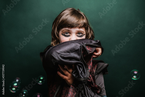 Little girl in enchantress dress with makeup looking at camera