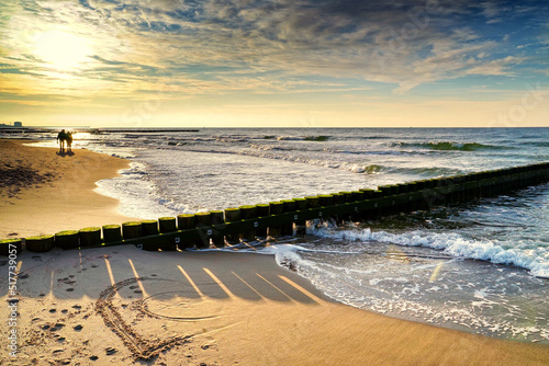 Fototapeta Naklejka Na Ścianę i Meble -  A couple in love walking down the beach and a heart drawn in the sand