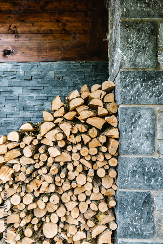 Stack of woodpile near stone wall in rural house photo