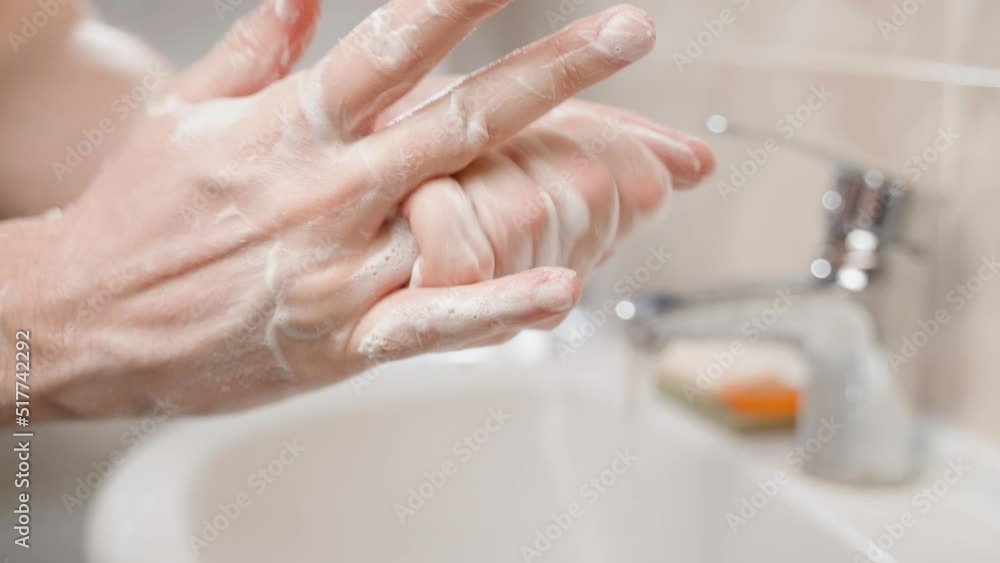 Thorough long-term washing of hands with a soapy solution close-up against the background of a white sink Thorough long-term washing of hands with a soapy solution close-up against the background of a white sink