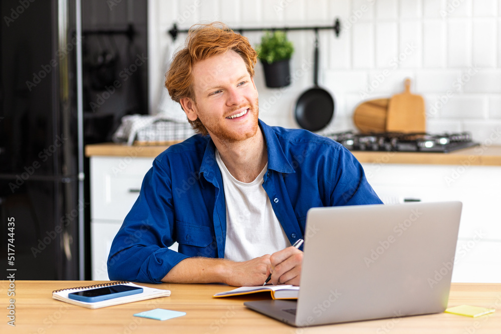 Happy male student using laptop computer, studying, distance learning. Redhead man freelancer working from home, looks away and thinks about something. Online education, smiling Happy male student using laptop computer, studying, distance learning. Redhead man freelancer working from home, looks away and thinks about something. Online education, smiling