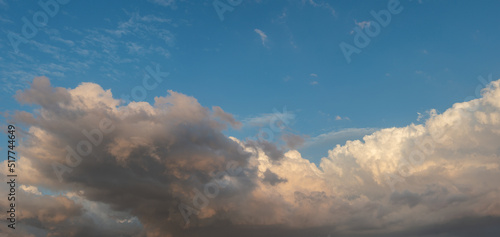 Banner with panoramic view over deep blue clean sky with illuminated clouds as a background.