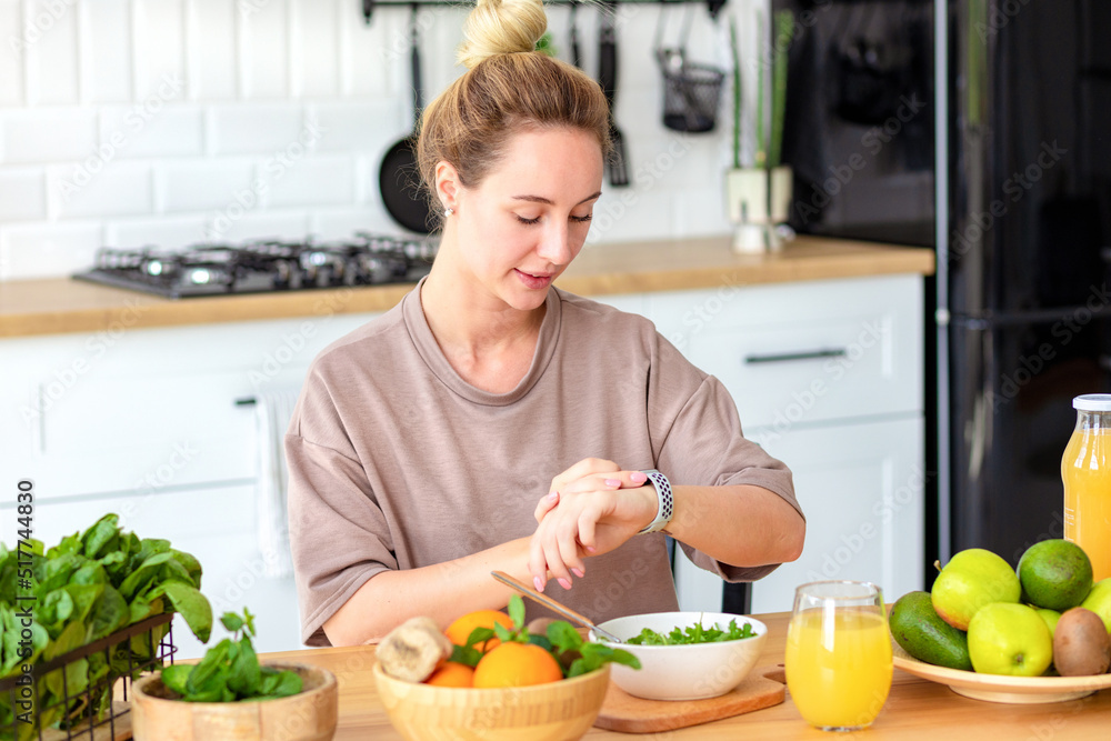 Healthy lifestyle concept. Beautiful young woman controls the calories she consume sitting at the kitchen table at home. Eating fresh healthy diet food Healthy lifestyle concept. Beautiful young woman controls the calories she consume sitting at the kitchen table at home. Eating fresh healthy diet food