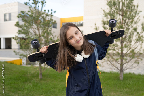 Smiling girl with longboard standing on street