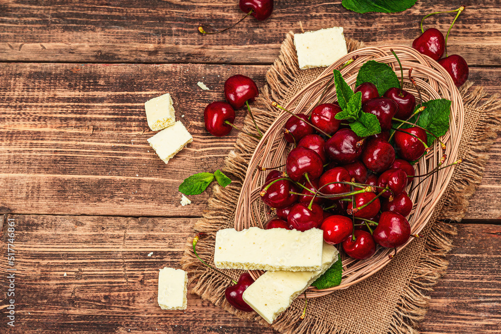 Ripe sweet cherries with fresh mint leaves and white chocolate, traditional summer fruits