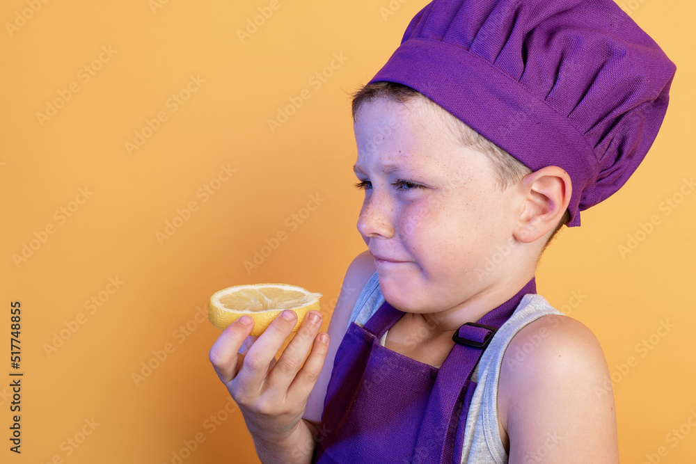 Cute little kid eating lemon slice in yellow studio Cute little kid eating lemon slice in yellow studio
