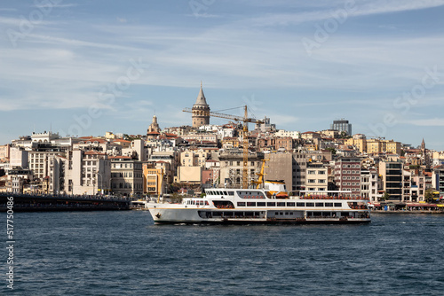 View of a traditional ferry boat on Golden Horn part of Bosphorus in Istanbul. Galata tower and Beyoglu district are in the view. It is a sunny summer day.