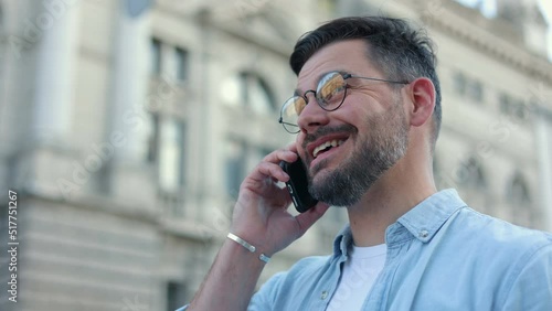 Portrait of cheerful happy Caucasian tourist man in glasses wearing casual clothes talking on phone, background of old city . Tourist concept. Traveling. Observing