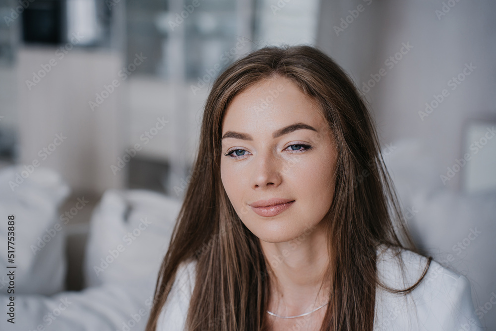 Fototapeta premium Close up portrait of European purposeful young blonde woman in white suit looking aside internally balanced after psychotherapist session. Healthy student girl dreaming about happy future at home.