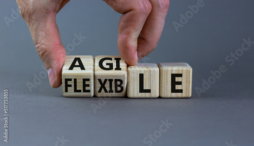 Flexible and agile symbol. Concept words Flexible and agile on wooden cubes. Businessman hand. Beautiful grey table grey background. Business flexible and agile concept. Copy space.