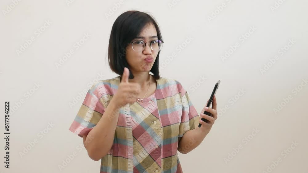 Asian woman standing while showing her cell phone with green screen Asian woman standing while showing her cell phone with green screen