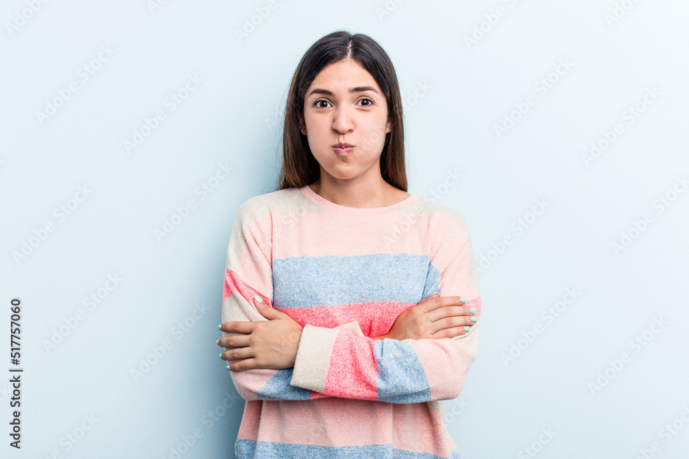 Young caucasian woman isolated on blue background blows cheeks, has tired expression. Facial expression concept. Young caucasian woman isolated on blue background blows cheeks, has tired expression. Facial expression concept.