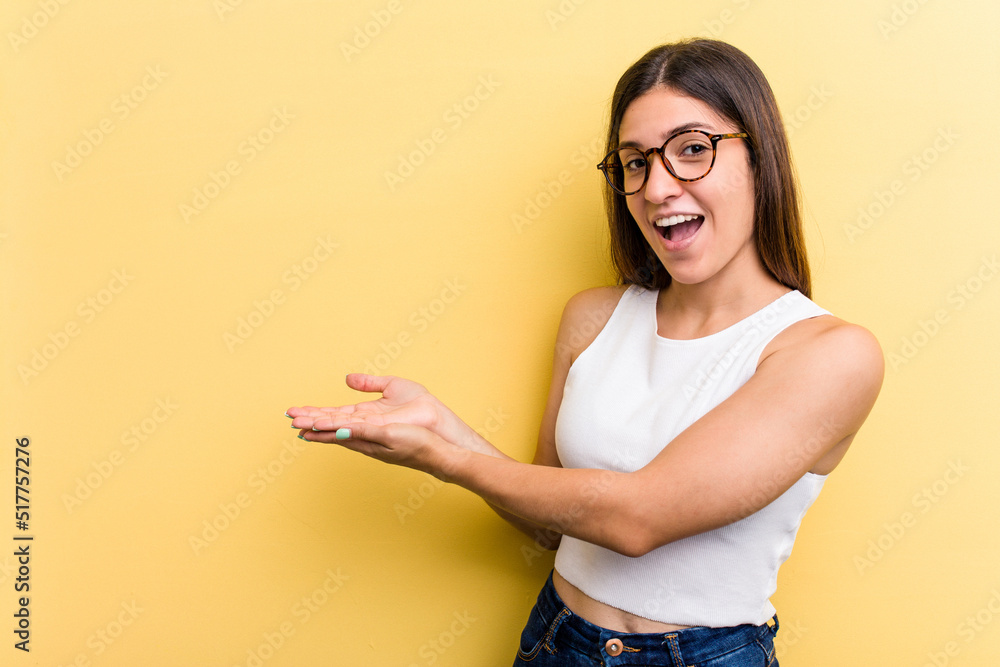 Young caucasian woman isolated on yellow background holding a copy space on a palm.