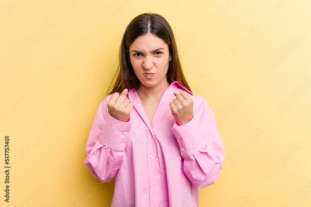 Young caucasian woman isolated on yellow background upset screaming with tense hands. Young caucasian woman isolated on yellow background upset screaming with tense hands.