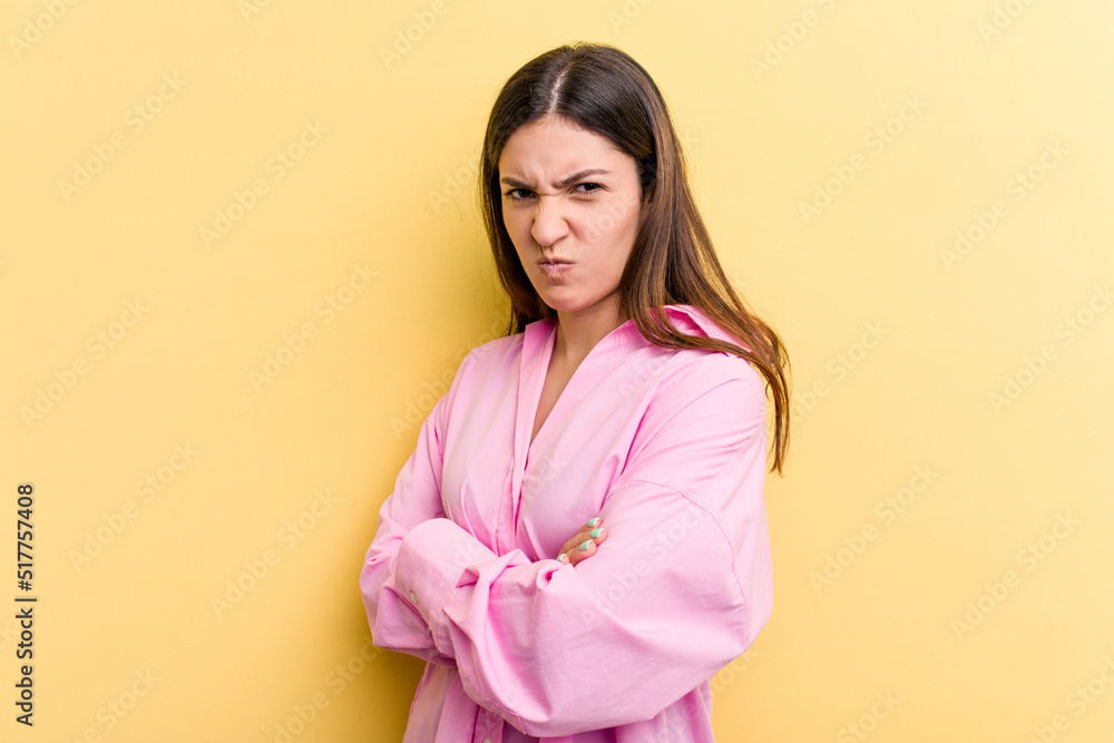 Young caucasian woman isolated on yellow background frowning face in displeasure, keeps arms folded. Young caucasian woman isolated on yellow background frowning face in displeasure, keeps arms folded.