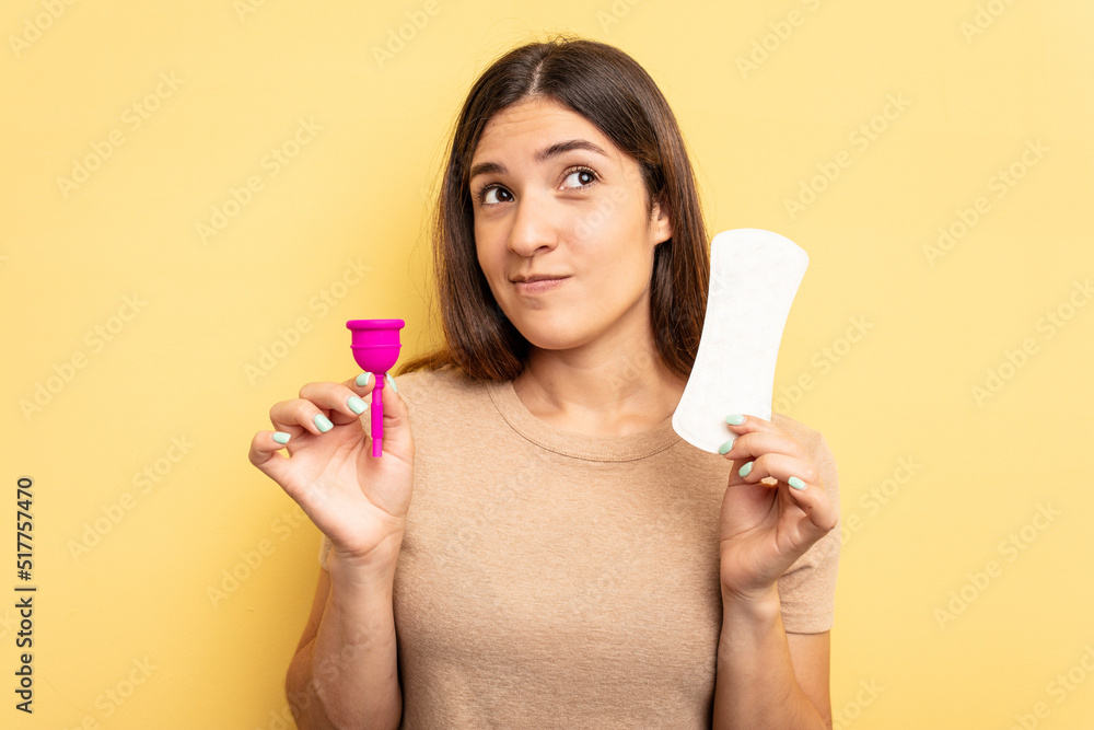 Young caucasian woman holding a menstrual cup isolated on yellow background Young caucasian woman holding a menstrual cup isolated on yellow background