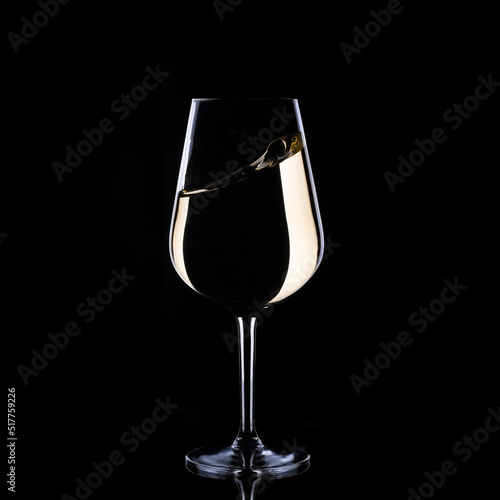 white wine splash in glass isolated on black background