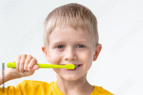 A cute caucasian little child is brushing his teeth with a toothbrush.