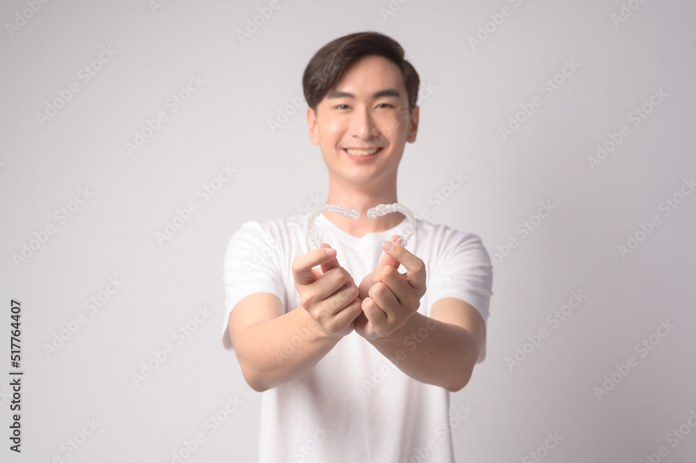 Young smiling man holding invisalign braces over white background studio, dental healthcare and Orthodontic concept.. Young smiling man holding invisalign braces over white background studio, dental healthcare and Orthodontic concept..