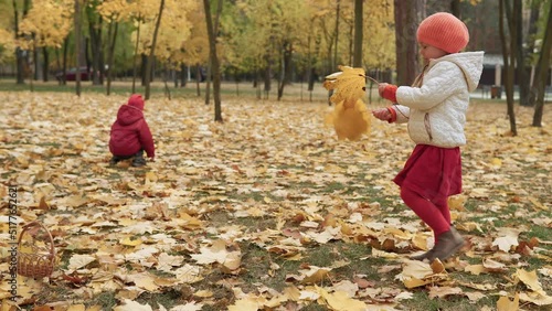 Two happy funny children kids boy Girl walking in park forest enjoying autumn fall nature weather. Kid Collect falling leaves in baskets, looking for harvest of mushrooms playing hiding behind trees