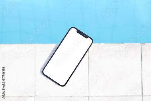 Mockup of a blank white screen smartphone close to a pool