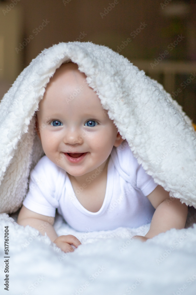 smiling baby looking at camera under a white blanket, towel. selective focus smiling baby looking at camera under a white blanket, towel. selective focus