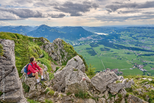 nice senior woman hiking at Mount Gruenten in the Allgaeu Alps with awesomw view over Iller valley to Lake Alpsee and Lake of Constanz, Bodensee,  Bavaria, Germany © Uwe