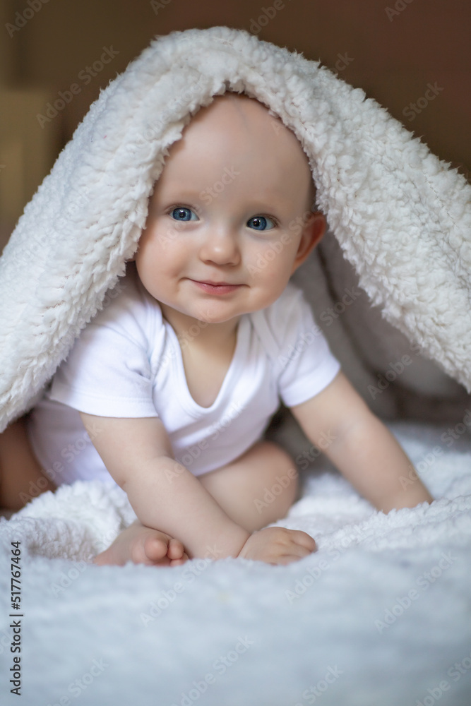 smiling baby looking at camera under a white blanket, towel. selective focus smiling baby looking at camera under a white blanket, towel. selective focus